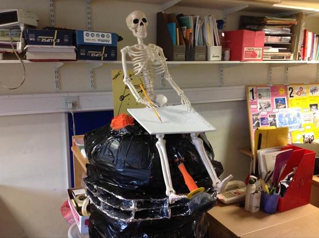 The image is entitled: ‘Image 02: The Hopeless University. Credit: Authors’ Personal Archive.’ It shows part of an office, now deleted, with creative and playful resources: a home-built Dalek with a plastic skeleton sitting on top while holding pen and paper.